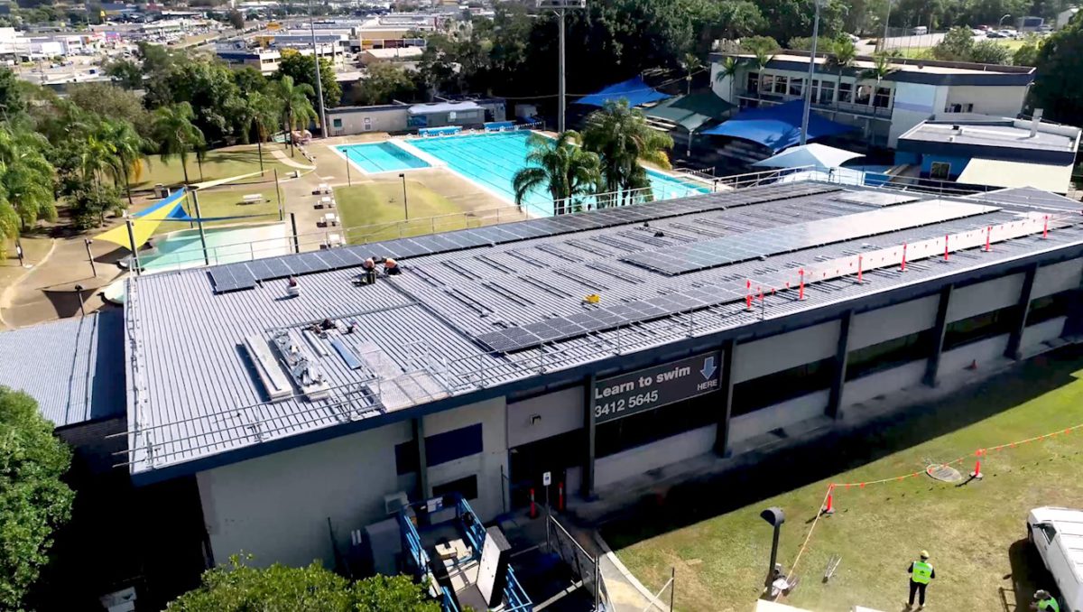 Workers install the 303 solar panels on the roof of Logan North Aquatic Centre
