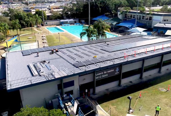 Workers install the 303 solar panels on the roof of Logan North Aquatic Centre