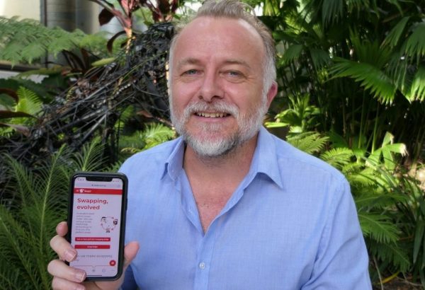 Entrepreneur Nicholas Robertson pictured with his SwapU app displayed on a phone.
