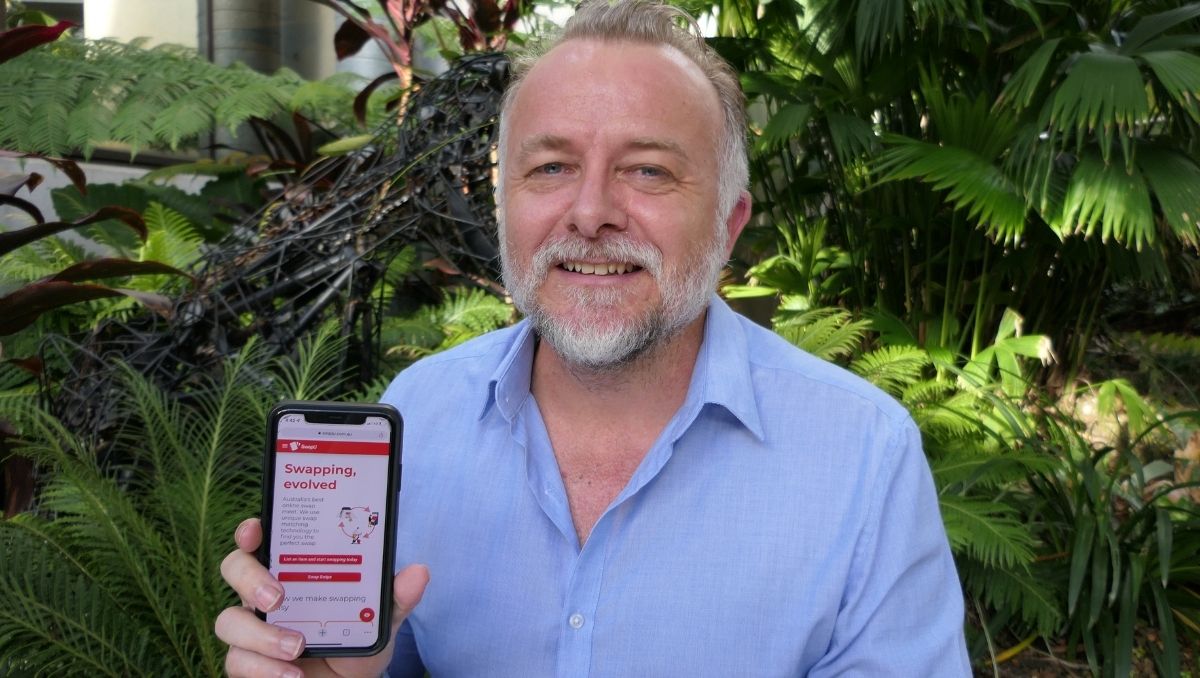 Entrepreneur Nicholas Robertson pictured with his SwapU app displayed on a phone.