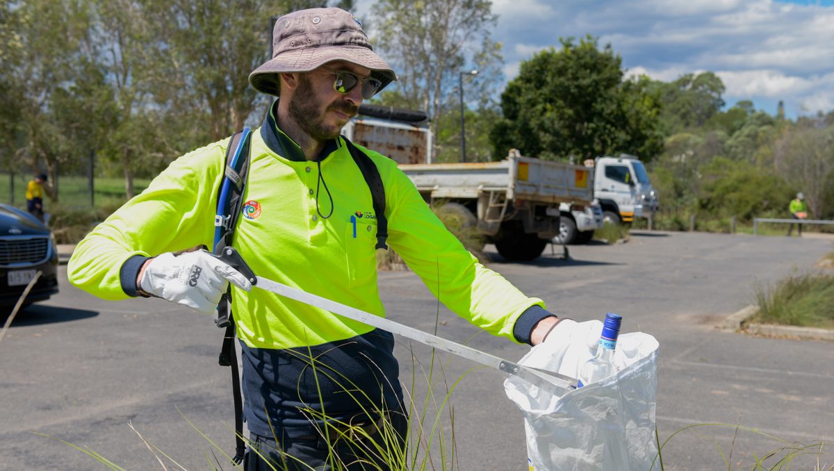 A Council officer works to clear a City of Logan park of flood debris.