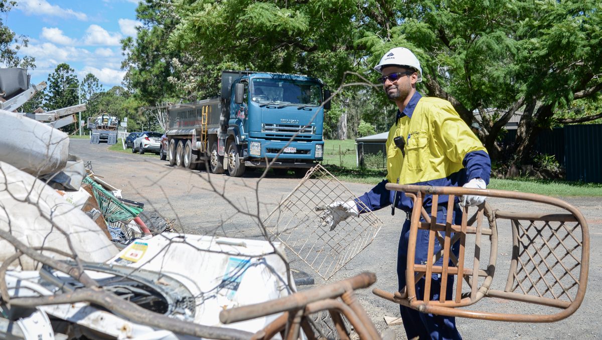 man carries chair to rubbish