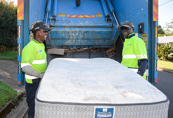 An image of Morris Jonson (left) and Ochan Obali removing a mattress during a kerbside collection at Shailer Park to demonstrate that matresses will now be recycled rather than sent to landfill..
