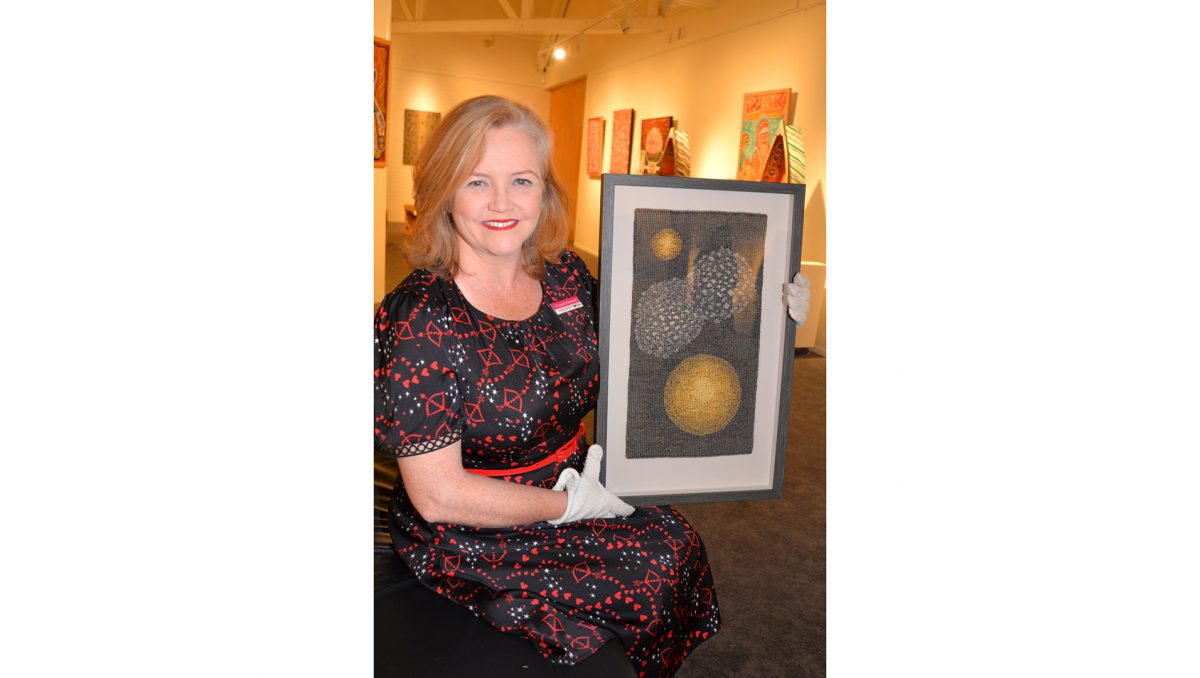 Cr Laurie Koranski holding one of the works of the late Robyn Daw.