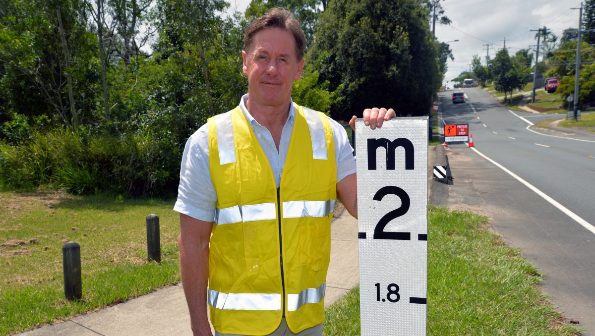 An image of Mayor Darren Power standing next to a flood marker on the one-year anniversary of the 2022 floods