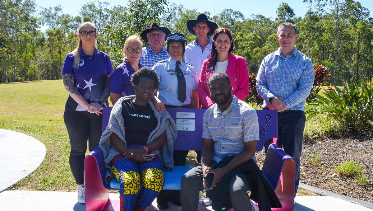 Linda and Hadrian Obi sit on the bench seat at Spring Mountain, which honours the memory of Stanley Obi and raises awareness of domestic and family violence. Behind them are (from left) Defenders for Hope representatives Elise Smith and Kathy Smith, Spring Mountain resident Peter Conohan, Acting Senior Sergeant Natalie Cole, Spring Mountain resident Nathan Kliese and Councillors Natalie Willcocks and Tim Frazer.