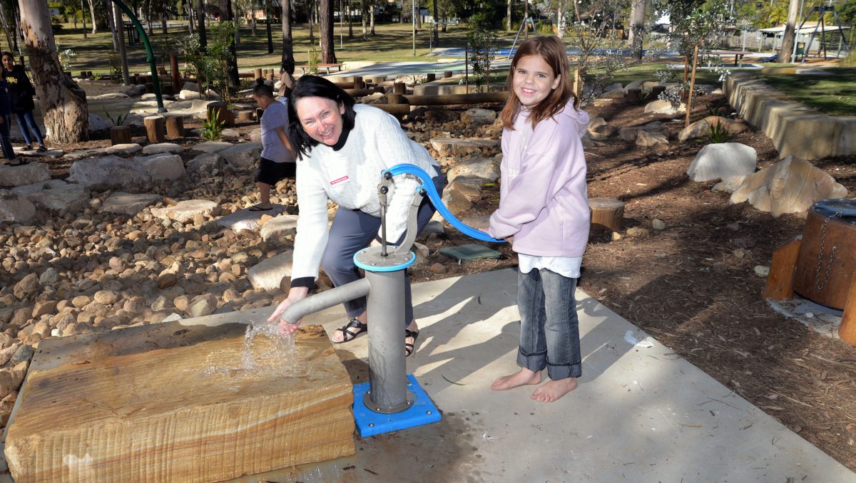 An image of Councillor Teresa Lane using one of the new water play pumps with Jade Harper, 10, in Eridani Park at Kingston which has undergone a $1.7 million upgrade.