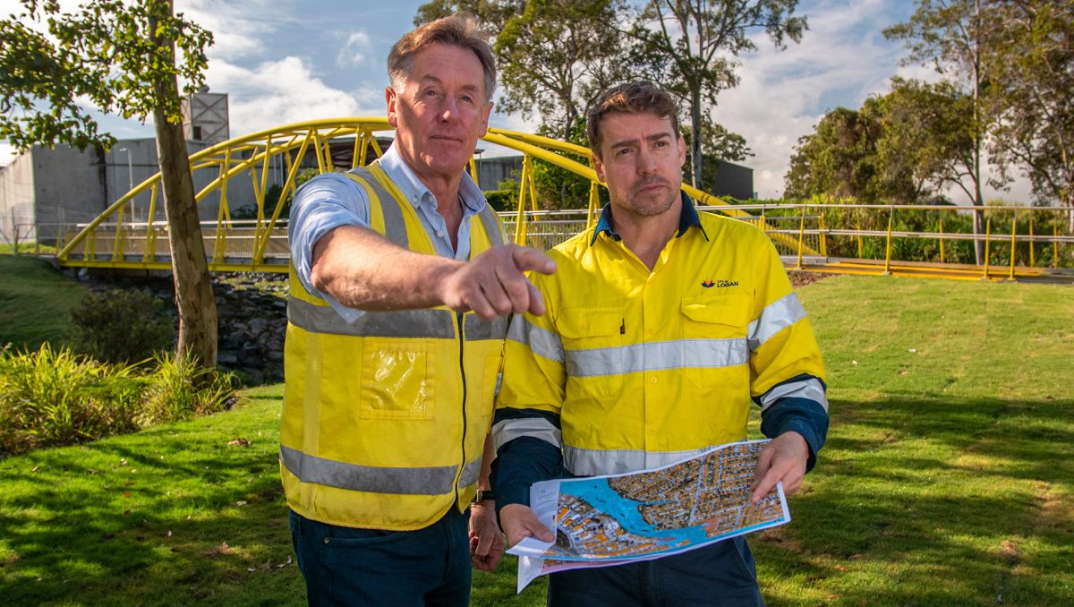 City of Logan Mayor Darren Power examines a flood-risk map with hydrographer Dominic Morris at Slacks Creek.