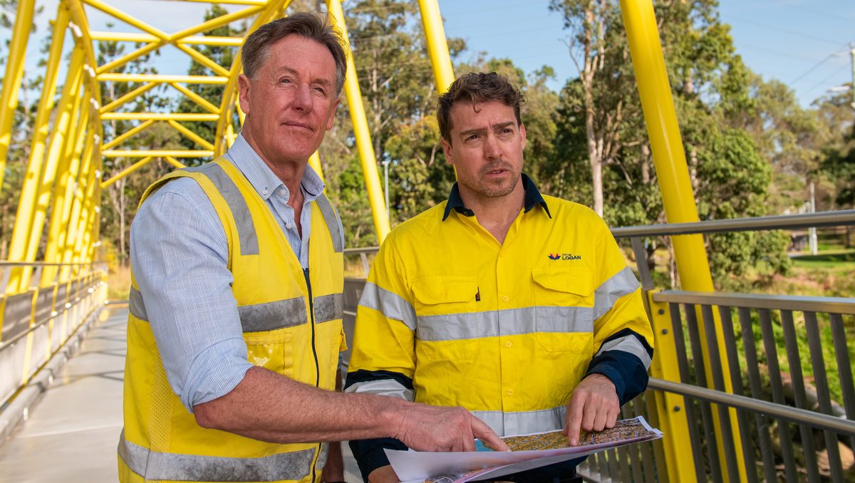 City of Logan Mayor Darren Power examines a flood-risk map with hydrographer Dominic Morris at Slacks Creek.