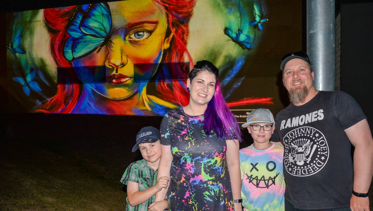 Jimboomba artist Stacey Bennett with husband Ross, and sons Jacob (left) and Noah in front of her artwork, 'The Butterfly Effect', which is part of the new lighting projection in Slacks Creek.