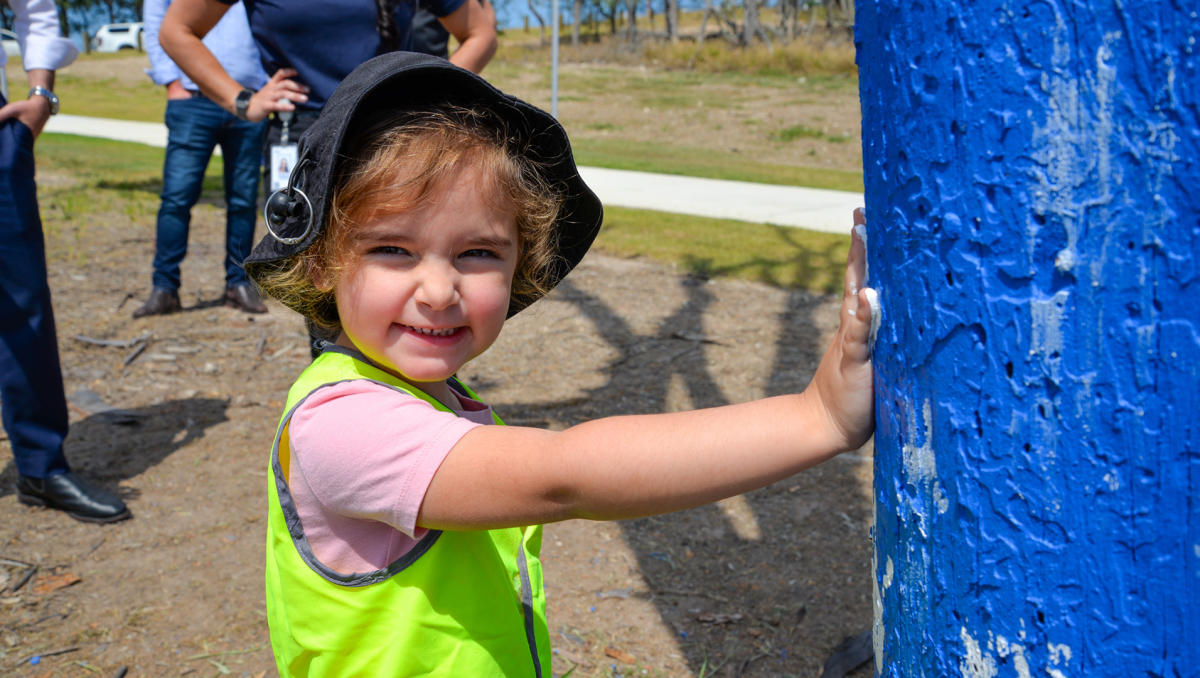 Logan Reserve youngster Ella Ugarak, 3, adds her handprint to the blue tree in Loganview Park at Logan Reserve.