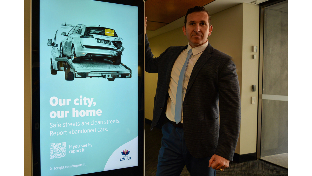 Logan City Council Lifestyle Chair Councillor Tony Hall with one of the promotional billboards for the Our City, Our Home campaign which will support the work of the new Rapid Response Taskforce.