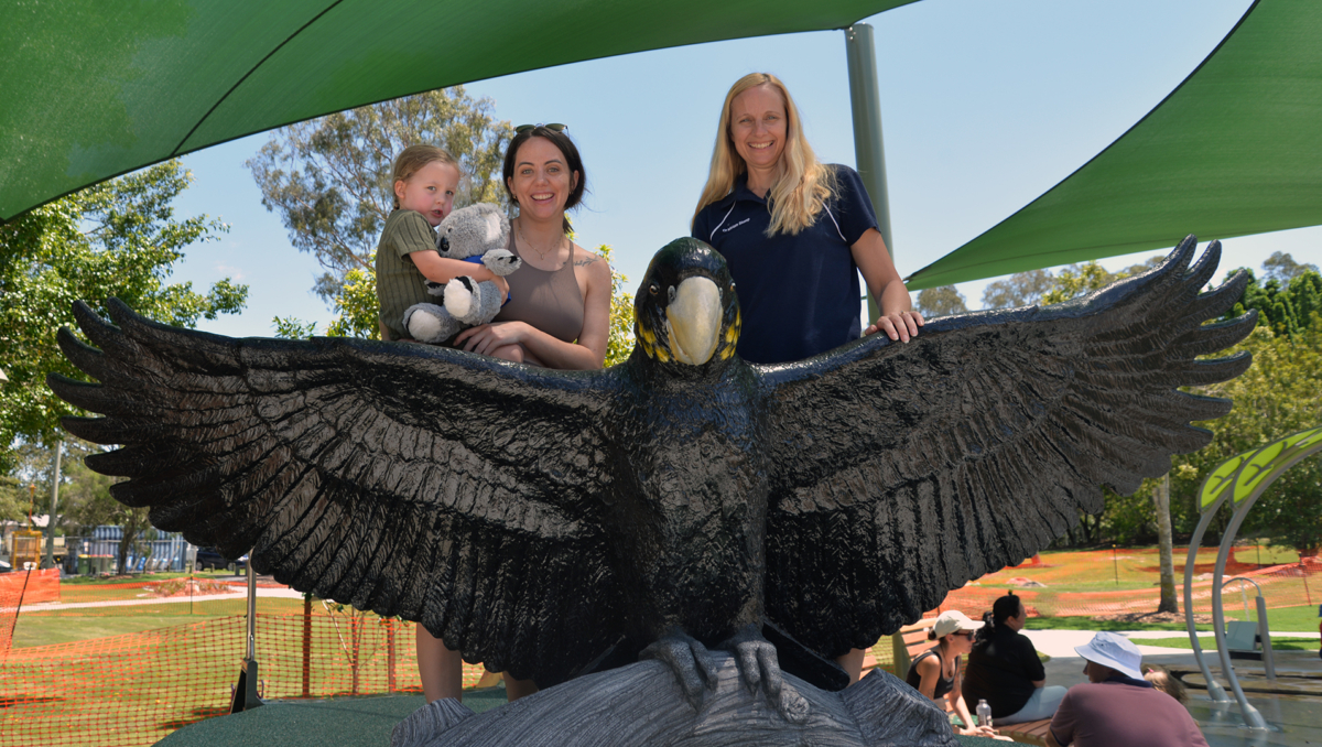 Cr Miriam Stemp on the parrot sculpture at ACP with Tammy and Sonny, 3, Campbell of Loganholme.