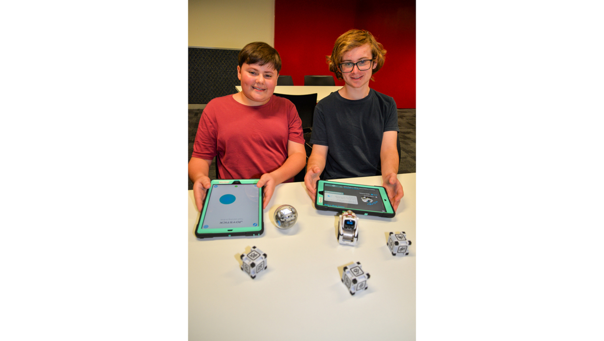Jimboomba brothers Samuel (left) and William Burgess with Logan Libraries’ robots which will feature in workshops during the April school holidays.