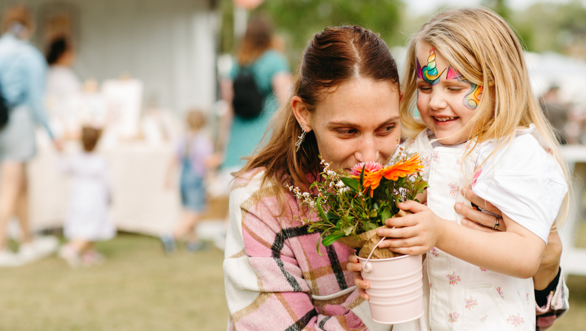 A mother and daughter at the markets smelling flowers