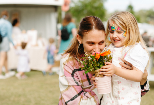 A mother and daughter at the markets smelling flowers