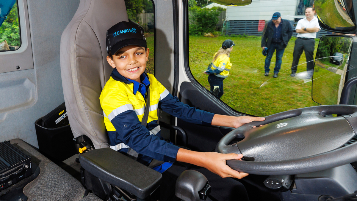 An image of Ethan Nilsen taking the steering wheel inside the garbage truck cabin.