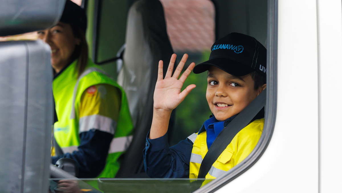 An image of Ethan Nilsen wavings as he heads to school in a garbage truck.