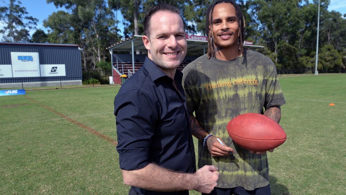 An image of City of Logan Mayor Jon Raven (left) getting an autographed souvenir football from retired NFL star Kenny Still at the Logan City Council-supported NFL Flag trial session at Marsden State High School today.