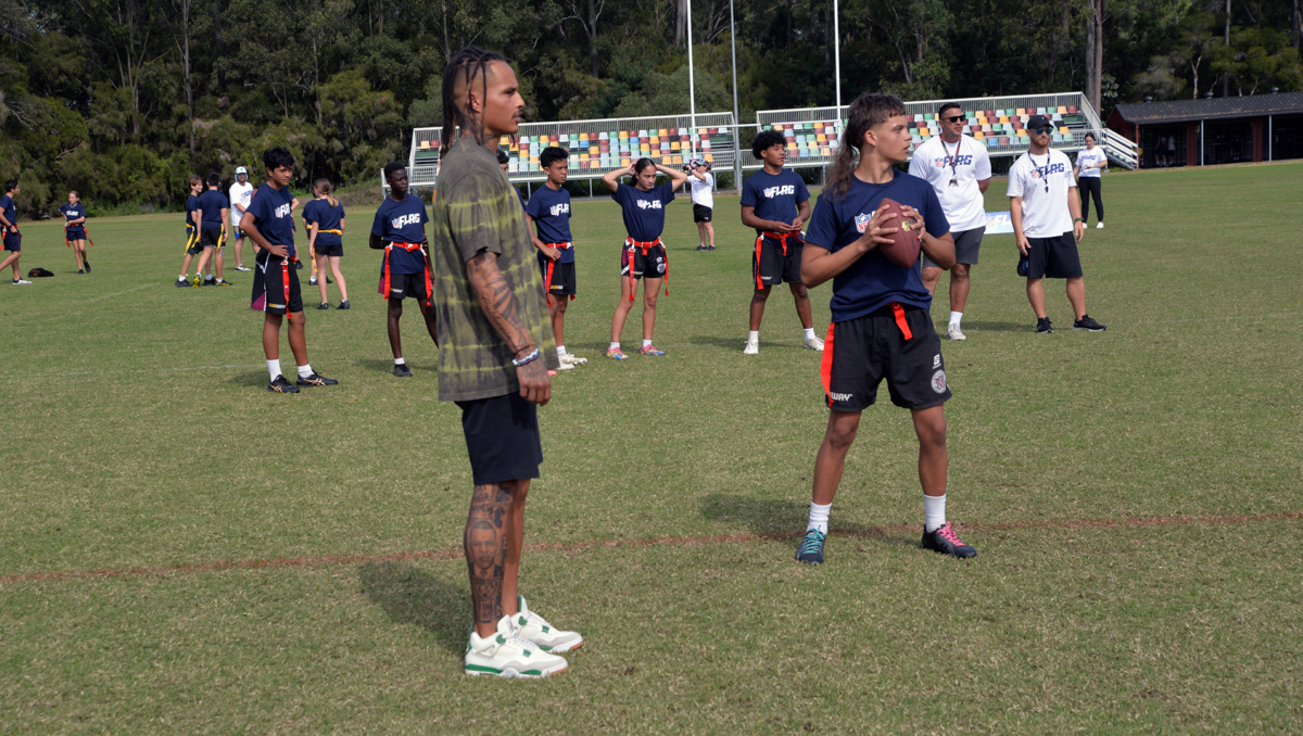 An image of Local teenagers trying out their American football skills in front of retired NFL wide receiver Kenny Stills.