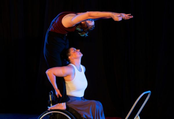 Women in wheel chair holds feet of woman bending backwards over the wheelchair